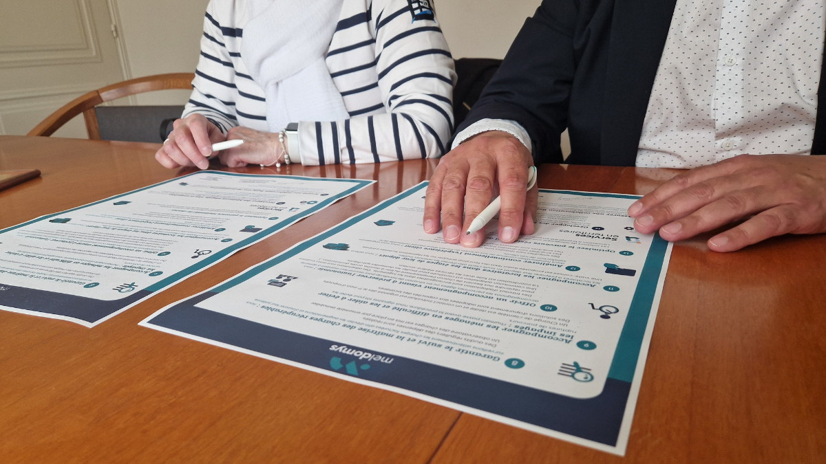 Un homme et une femme signant la charte qualité du groupe Meldomys